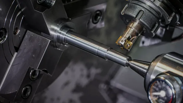 Detailný záber na obrábanie kovového dielu v CNC sústruhu