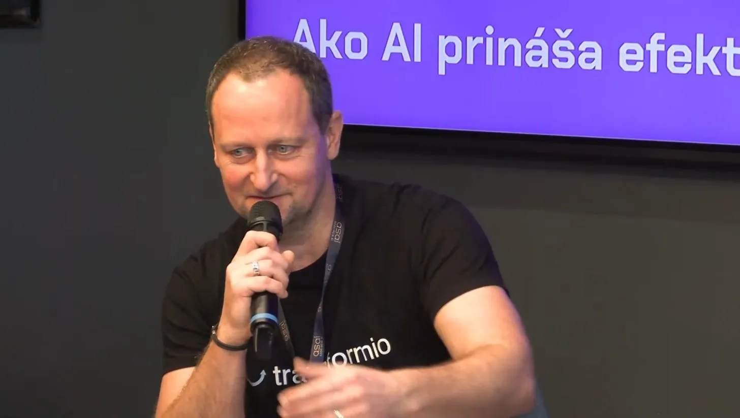 Braňo Šmidt zblízka s mikrofónom v ruke, usmieva sa.