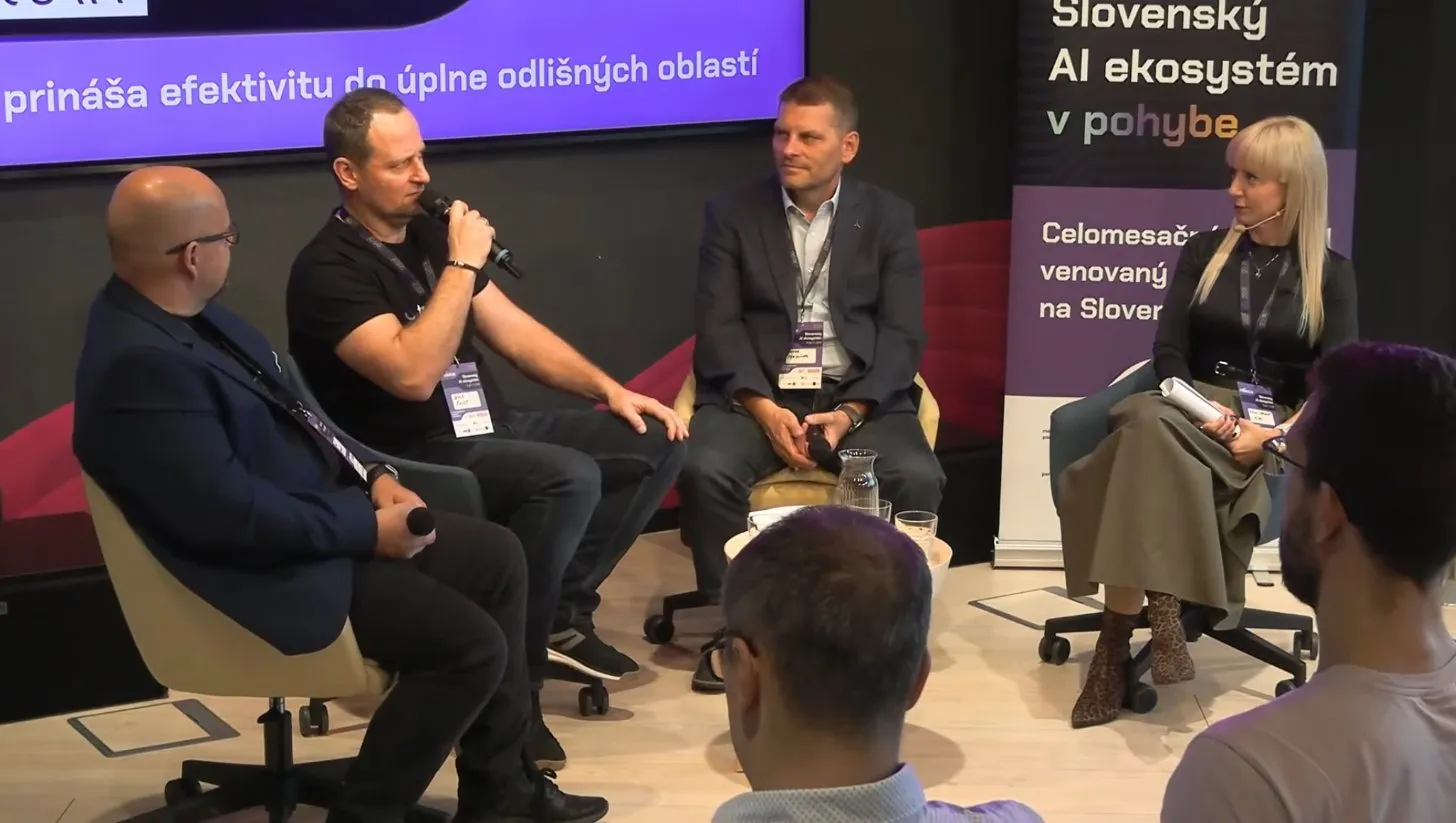 Braňo Šmidt hovorí do mikrofónu počas panelovej diskusie, vedľa neho sedia ďalší diskutujúci.